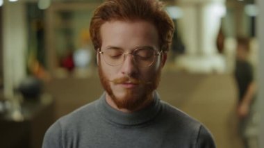 Kızıl saçlı işadamı kameraya bakıyor. Pozitif bilişim uzmanı kameraya gülümsüyor