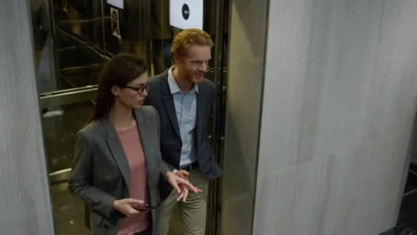 Бизнесмен и деловая женщина разговаривают в лифте. Коллеги выходят из лифта — стоковое видео