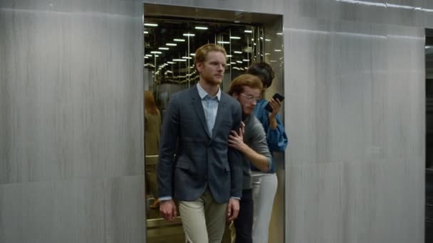 Деловые люди выходят из лифта в коридоре. Бизнесмен спешит на встречу — стоковое видео