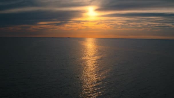 Ocean surface against peaceful cloudy sky with yellow sun. Ocean reflecting sun. — Stock Video