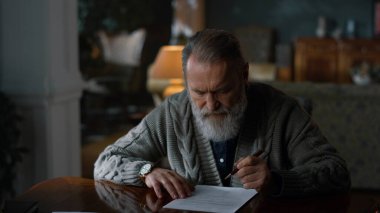 Odaklanmış beyefendi evrak dolabında çalışıyor. Yaşlı adam kontratı kontrol ediyor..