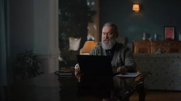 Senior man having online conference on laptop computer. Old business man