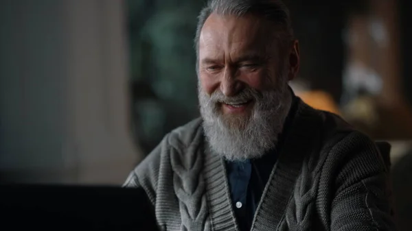 Un viejo alegre recibiendo videollamadas a casa. Feliz caballero usando la computadora en el interior. —  Fotos de Stock