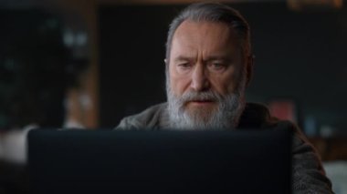 Bilgisayar dolabında çalışan kıdemli adam. Eski iş adamı dizüstü bilgisayar kullanıyor..