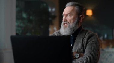 Klasik ev odasındaki bilgisayardan video görüşmesi sırasında sert yaşlı adam konuşuyor..