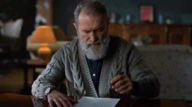 Yaşlı beyefendi lüks evi okuyor. Belgelerde çalışan yaşlı adam