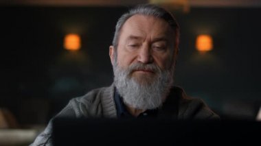 Üst düzey adam bilgisayar ekranlı ev dolabına bakıyor. Bilgisayar kullanan yaşlı işadamı.