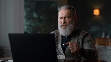Lüks oturma odasındaki bilgisayarda video görüşmesi yapan katı yaşlı bir adam..