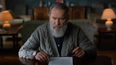 Evrak işleriyle uğraşan düşünceli yaşlı bir beyefendi. Üst düzey imzalı belge.