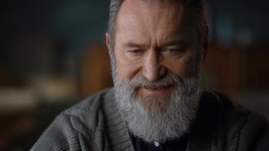 Yaşlı adam evde bilgi topluyor. Uzaktan kumandalı, gri saçlı bir adam.