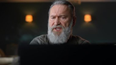 Eski bir iş adamı lüks oturma odasında bilgisayar kullanıyor..