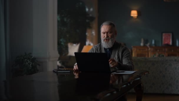 Starszy biznesmen mając wideo rozmowy na laptopie w luksusowym domu — Wideo stockowe