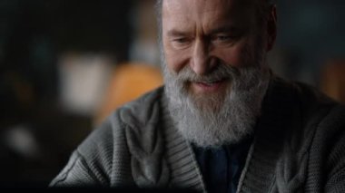 Portre mutlu yaşlı adam çalışırken gülerek ev içi bilgisayar.