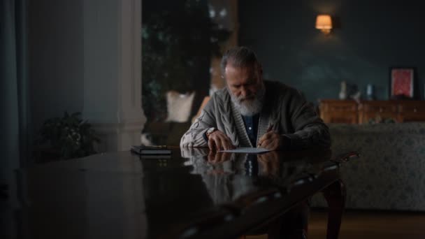 Viejo pensativo trabajando documentos en el gabinete. Hombre mayor escribiendo carta en casa — Vídeo de stock