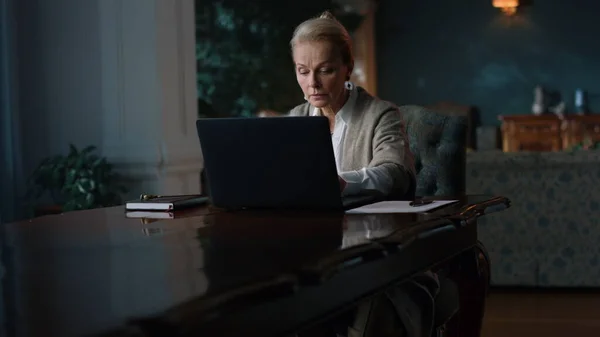 Rico mulher madura digitando laptop em casa. Greyhaired senhora trabalhando gabinete de computador. — Fotografia de Stock