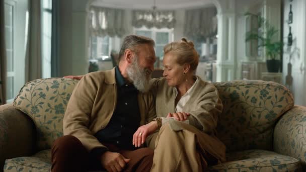 Pareja de ancianos sonrientes hablando en el sofá en la sala de estar. Personas mayores felices — Vídeos de Stock