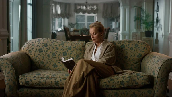 O femeie bătrână citind o carte în sufragerie de lux. Elegant doamnă având odihnă fotografii de stoc fără drepturi de autor