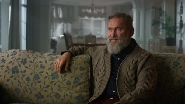 Schöner alter Mann sitzt Couch in Luxus-Haus. Reicher älterer Herr ruht sich aus — Stockvideo