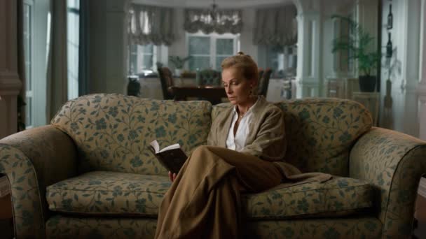 Stará žena čte knihu v luxusním obýváku. Elegantní dáma odpočívá — Stock video