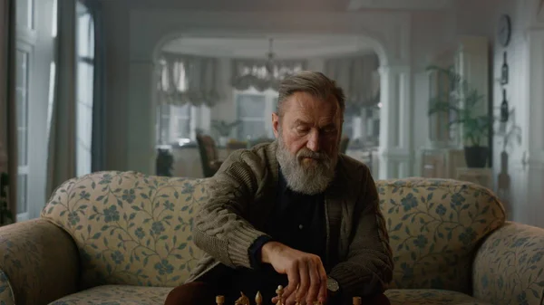 Yaşlı adam evde tek başına satranç oynuyor. Bilgelik emeklilik yaşam konsepti — Stok fotoğraf