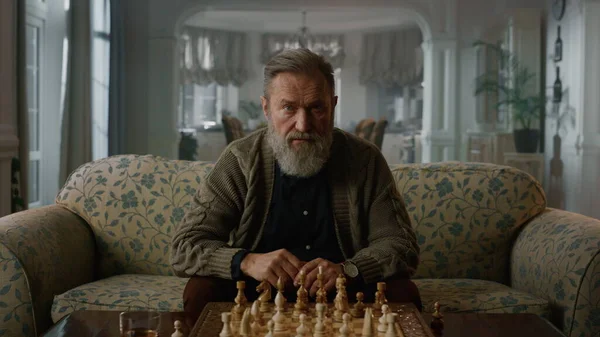En eftertänksam äldre man som tror att schackspelet är hemma. Senior spelare spelar schack — Stockfoto