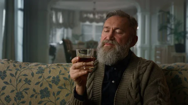 Oude zakenman zitbank met whiskey glas. Portret senior heer — Stockfoto