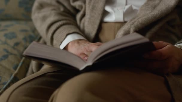 Closeup volwassen vrouw handen flippen boekpagina 's binnen. Oudere vrouw leest — Stockvideo