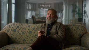 Zengin kıdemli adam emeklilik konyağının tadını çıkarıyor. Kendinden emin yaşlı beyefendi içiyor.