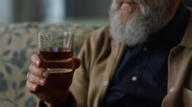 Ellerinde cam viski tutan yaşlı bir adam. Dinlenme emeklilik konseptinin tadını çıkar