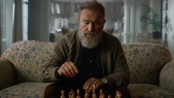 Starší muž hraje šachy sám v klasickém obýváku. Zaostřený dospělý gentleman — Stock video