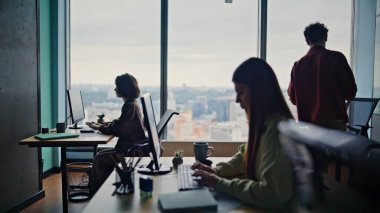 Yazılım geliştiricileri, bilgisayarlarda çalışan siluetleri parlak bir işbirliği kabinesinde birlikte kullanıyorlar. Çalışma alanındaki görevleri gözden geçiren kodları yazan odaklanmış takım. Panoramik pencereli modern şehir ofisi