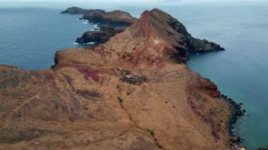Bulutlu gökyüzünün altındaki engebeli kıyı manzarası. Adada resimli sabah doğası. Mavi okyanus dalgaları kayalık kıyıları yıkıyor. Sakin, derin turkuaz su. Huzurlu deniz manzarasının doğal güzelliği 