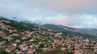 Bulutlu gökyüzü havasının altında resim gibi bir sahil kasabası. Bereketli yeşil dağların oradaki panoramik sabah köyü. Kasvetli bir günde sakin yamaçların insansız hava aracı görüntüsü. Yaz tepeleri arasında engebeli kıyı evleri 