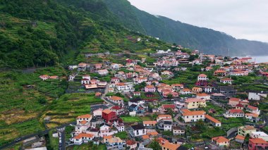 Orman kırsalında bulutlu bir günde doğa havası. Gökgürültüsü bulutlarının altında panoramik resimli dağ mimarisi manzarası. Yeşil ormanlık tepelere konmuş rahat evler. Taze vadi köyü ağır çekim