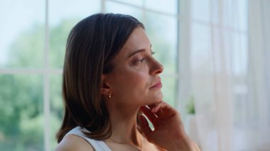 Portre dalgın esmer, aydınlık apartmanda oturuyor ve online projeyi düşünüyor. Yatak odasında bilgisayarla uzaktan yakından ilgilenen düşünceli bir kadın. Ciddi serbest çalışan yatakta kablosuz aygıtlara göz atıyor.