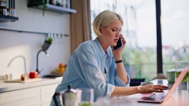 Uzaktan kumandayla konuşan akıllı telefon ev mutfağında klavyeye basıyor. Sarışın kadın mutfaktaki sözleşmeleri araştırmak için cep telefonuyla konuşuyor. Odaklanmış Serbest İşçi Çağrısı 