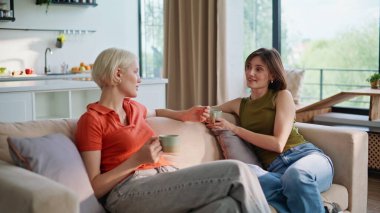 Sohbet eden kadınlar kanepenin iç tarafında çay içiyorlar. Sakin kızlar rahat bir dairede kahve fincanlarını yudumluyorlar. Hafta sonları Igbt çiftinin günlük haber dinlendirici kanepeyi tartışmasına bayılıyorum. Evdeki insanlar. 