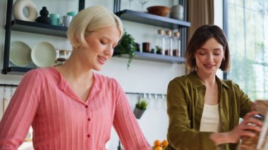 Güler yüzlü ev arkadaşları mutfakta durup gün ışığında sebze hazırlıyorlar. Heyecanlı çift içeride huzurlu bir kahvaltı yapıyor. Enerjik kız yeşillik kesiyor arkadaşı granola yapıyor