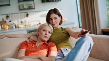 Rahat ablalar sabahları kanepede oturup kanalı değiştiriyorlar. Kumral kadının elinde uzaktan kumanda var. Kızlar kanepede birlikte televizyon izlemeyi seçiyorlar. Eğlence konsepti 