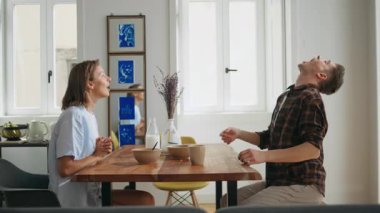 Mutlu eşler kahvaltı masasında gülüyor. Kaygısız sevgililer sabahları yemekle oynayıp eğleniyorlar. Neşeli adam ağzıyla böğürtlen yakalıyor. Genç aile beşlik çakıyor..