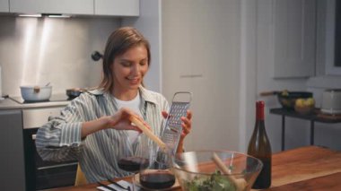 Gülümseyen kadın evde yemek yerken peynir rendeliyor. Sıcak mutfakta yemek yiyen çift yıldönümlerini kutluyor. Mutlu eş, bilinmeyen bir kocayla romantik bir randevuda zevkle yemek hazırlıyor. Mutlu aile tatilleri.