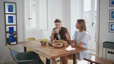 Gülen çift kahvaltısını yapıyor. Tasasız gençler, hafta sonlarını pijamalarıyla geçirmekten bahsediyorlar. Modern mutfakta kahve içmeyi seven bir adam güzel bir kız arkadaşı dinliyor..