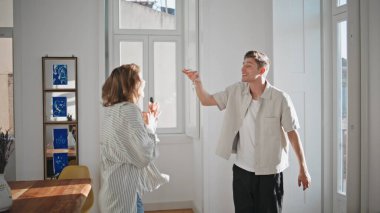 Mutlu çift eve taşınmayı kutlayarak dönüyor. Neşeli koca, modern bir dairede genç hanımı kucaklıyor. Mutlu aile taşınmamızı kutluyor. Gayrimenkul kredisi.