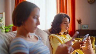 Cep telefonlarını karıştıran iki kadın hafta sonunu oturma odasında tembelce geçiriyorlar. Rahatlamış arkadaşlar akıllı telefonları kaydırarak haberleri tartışıyor. Kız kardeşler cep telefonu uygulamasını kullanarak çevrimiçi alışveriş yapmayı seviyorlar