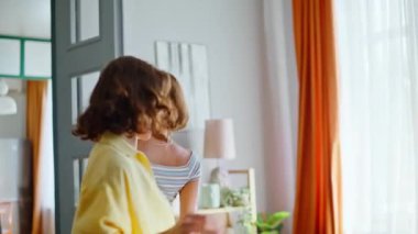 Neşeli kankalar modern apartman dairesinde dans ediyorlar. Evde hareketli ritmik müzik dinleyen iki kadının gülümsemesi. Duygusal arkadaşlar evde kız partisinden zevk alıyorlar. Aile içi hafta sonu eğlencesi.