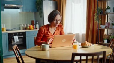 Aşırı sevinçli serbest çalışan dizüstü bilgisayarına göz atıyor. Eve yakın çekim için iş daveti alıyor. Mutfakta zafer kutlamaları yapan heyecanlı kadın ellerini kaldırıyor. Duygusal esmer görünümlü bilgisayar ekranı mutlu.