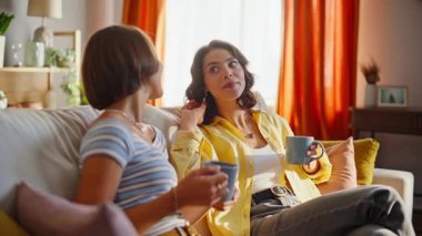 Kanepede konuşan dost canlısı bir çift kahve fincanlarını yakın plan çekiyorlar. Apartman kanepede sıcak içecek yudumlayarak gülen iki kadın. Mücevherat haftasonunu birlikte geçirmeyi tartışan olumlu arkadaşlar..