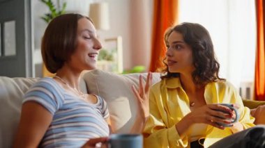 Gülümseyen esmer, kanepede yan yana oturan kankayla haberleri paylaşıyor. Neşeli iki arkadaş dedikoduları tartışıyor ve dostça iletişim kuruyorlar. Birkaç kadın kanepede kahve içiyor..