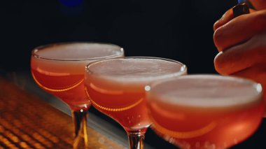 Gece barında çakmak kullanarak limon suyunu kokteyl üzerine sıçratan yaratıcı barmen. Bilinmeyen barmen elleri bardaki bardaklara ekşi şeyler ekliyor. Profesyonel hazırlık içeceği..