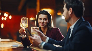 Closeup attractive woman flirting with young man in nightclub party. Relaxed couple holding beverage glasses in bar at evening. Smiling people drinking cocktails resting in restaurant. Date concept